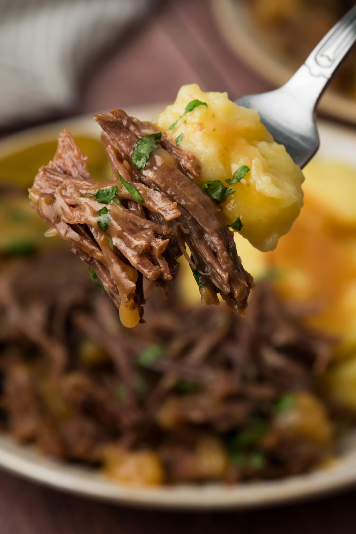 Fork with mashed potatoes and pot roast on it.