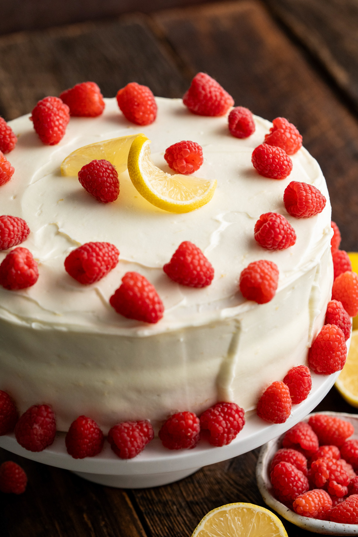 Lemon raspberry cake on a white cake plate.
