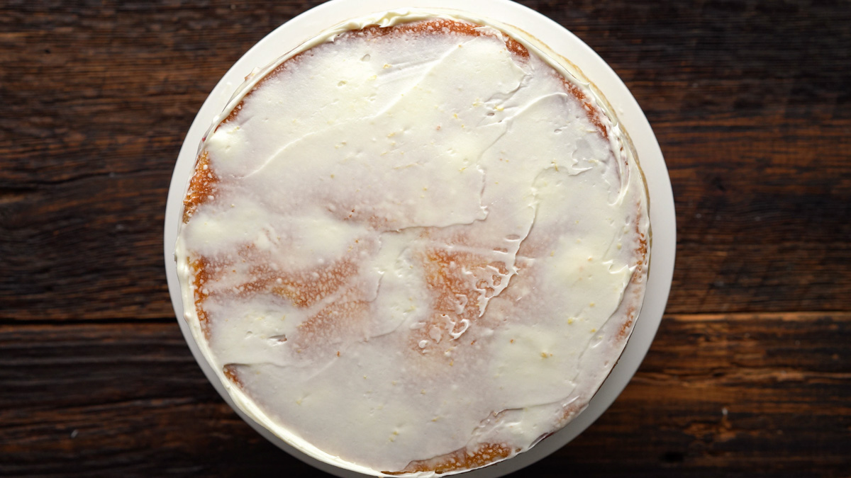 Crumb coat of frosting on the cake.