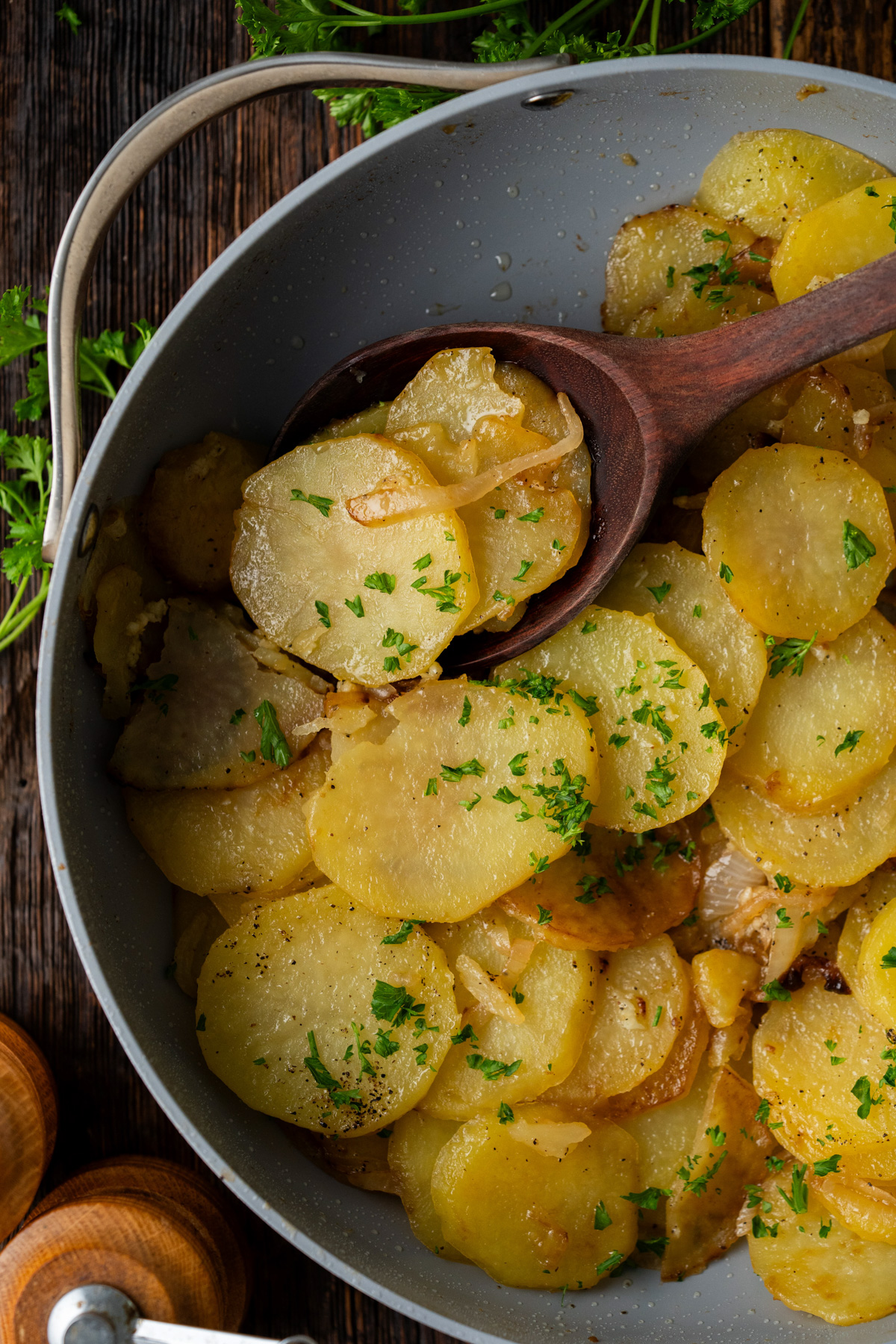 A skillet of smothered potatoes with fresh parsley on top.