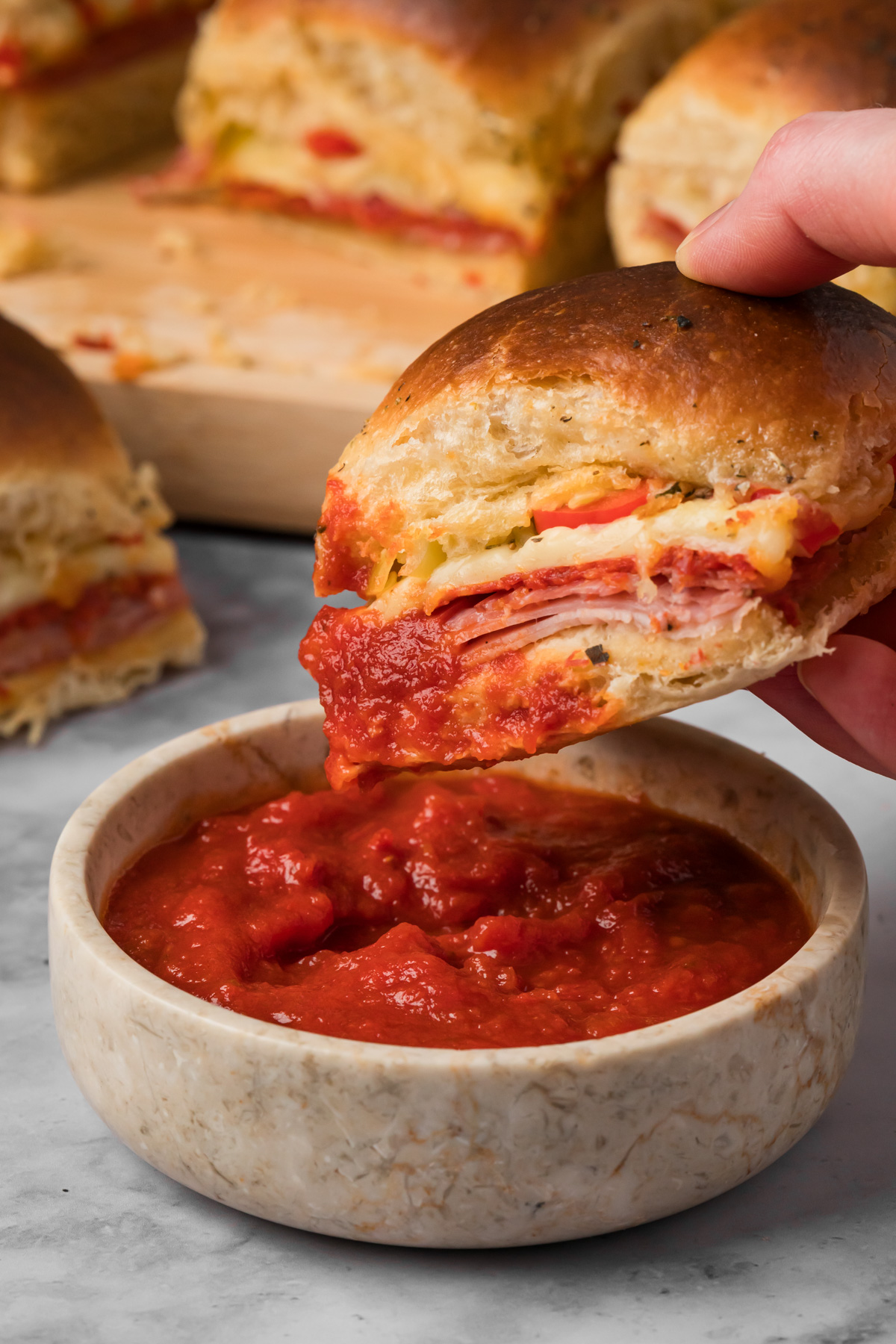 Italian slider being dipped into marinara sauce.