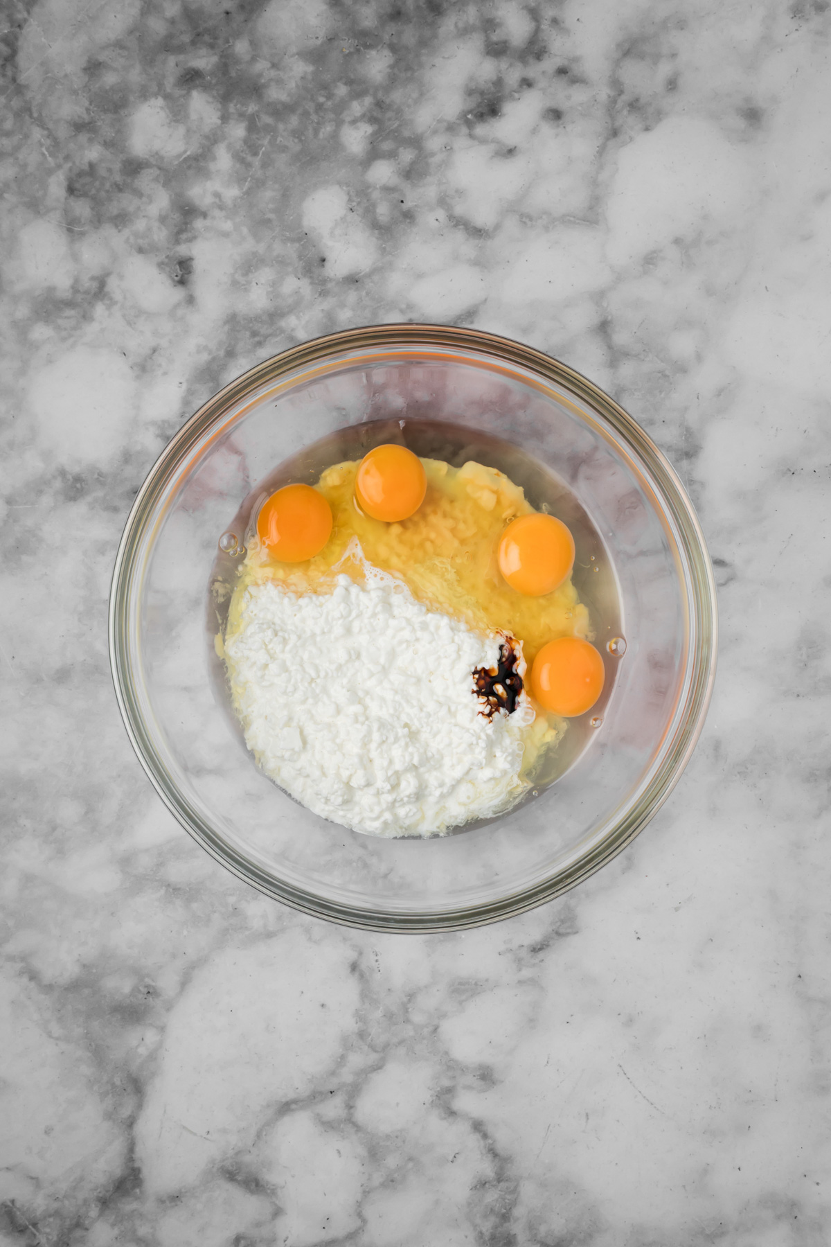 Cottage cheese, eggs, and vanilla in a glass bowl.