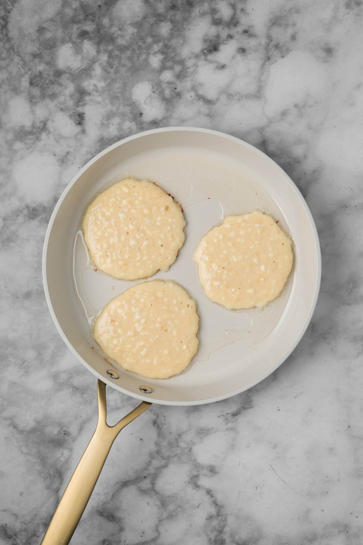 Banana pancakes cooking in a pan.