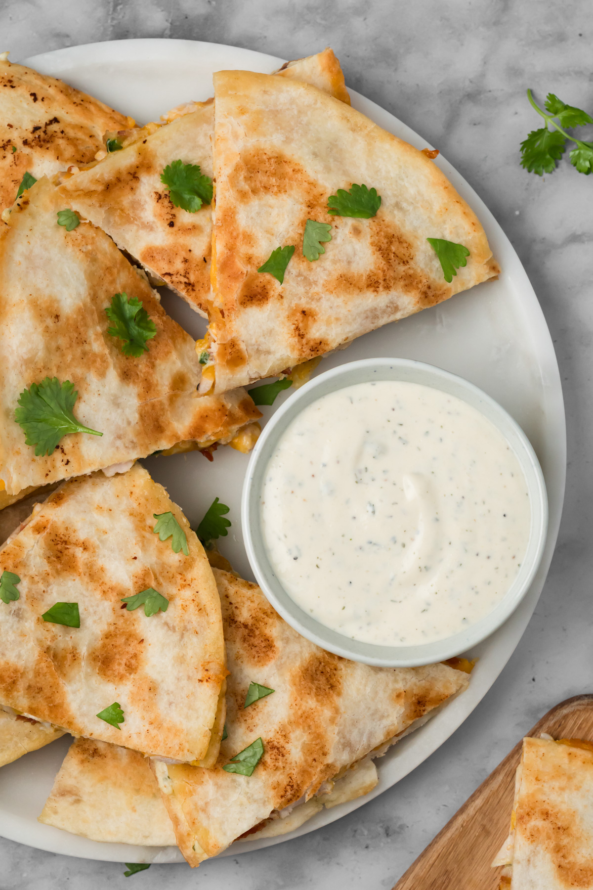 Chicken bacon ranch quesadillas on a white plate with a ranch dipping sauce.