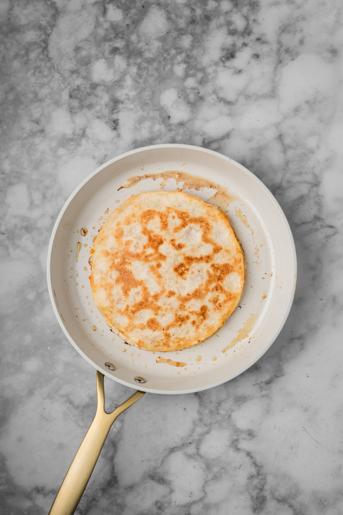 Golden brown quesadilla cooking in a skillet.