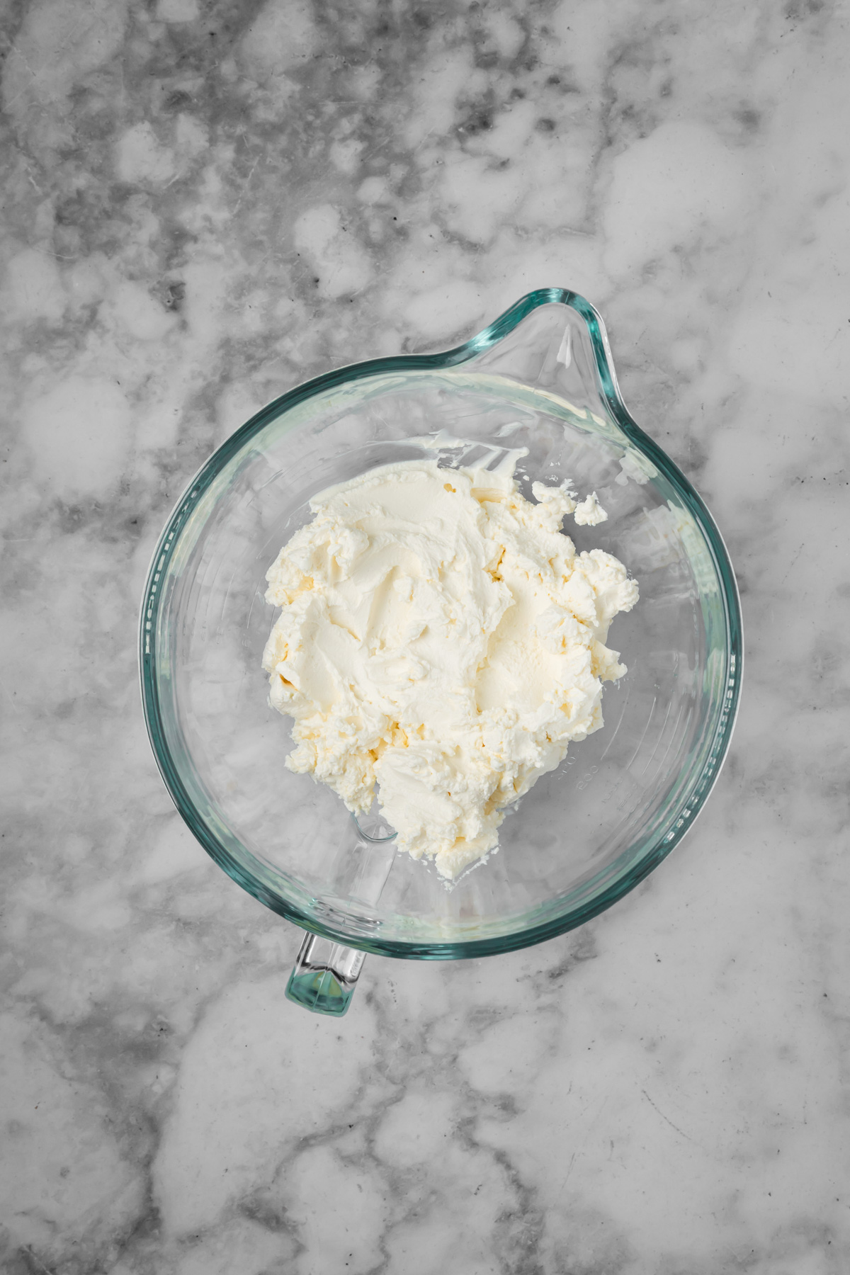 Cream cheese added to a glass mixing bowl.
