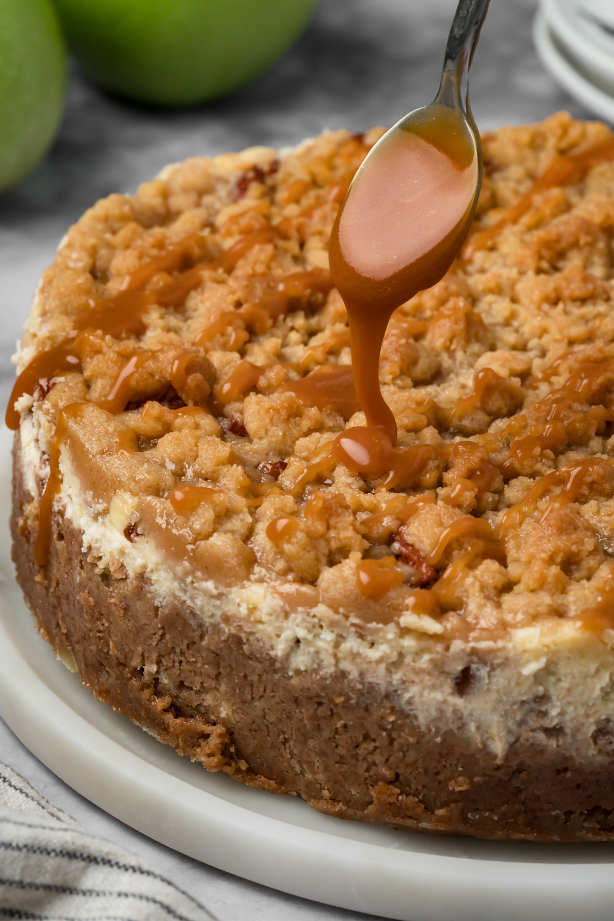 Caramel being spooned over a cheesecake.