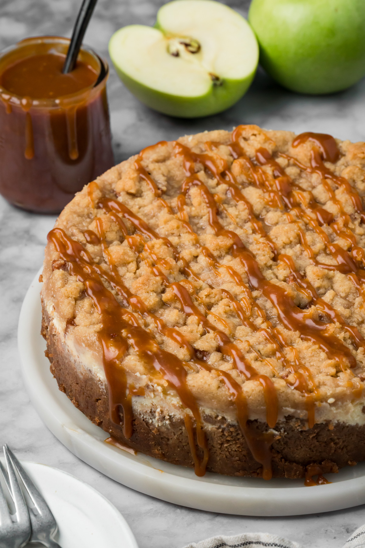 Apple crumble cheesecake with salted caramel sauce on top.