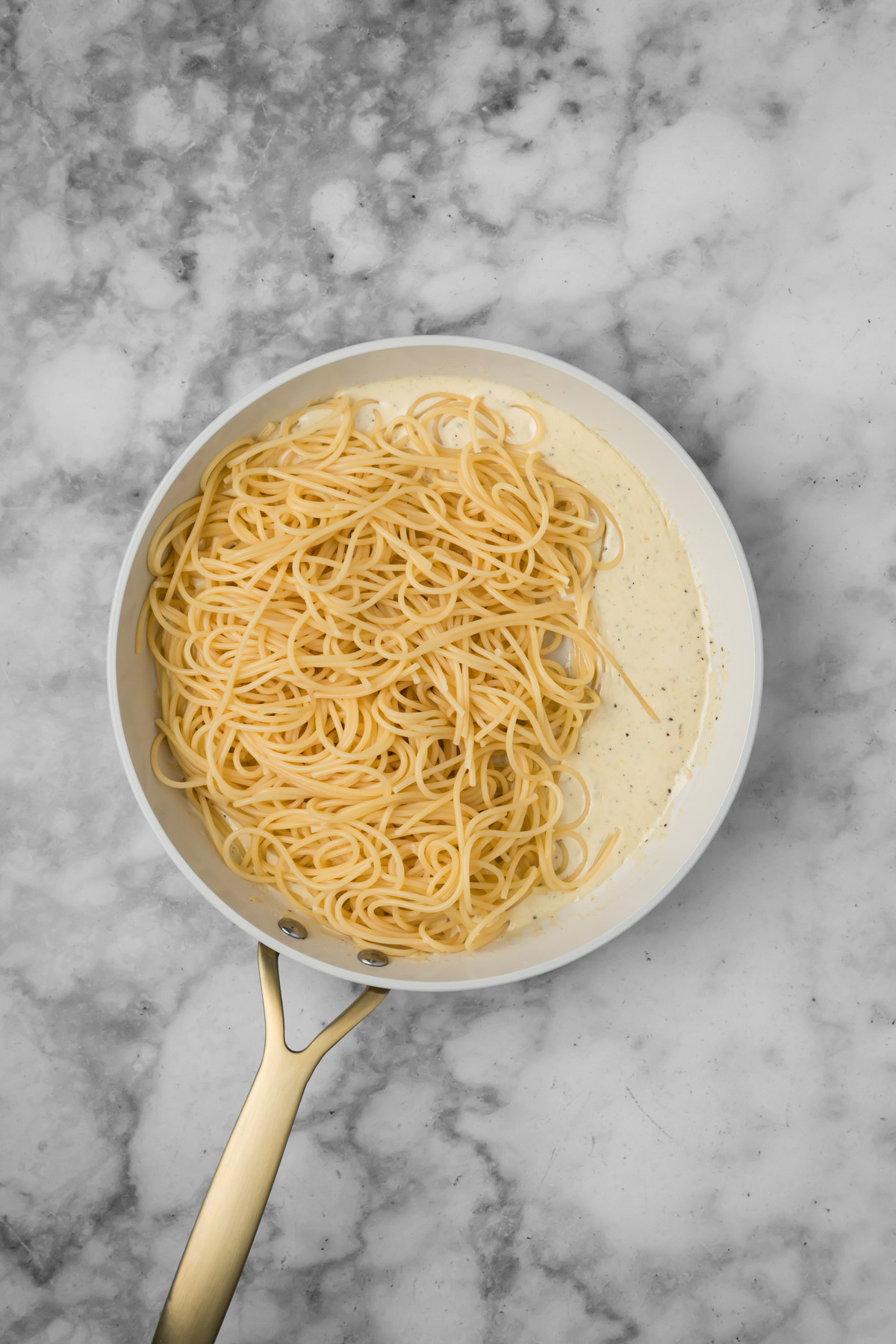 Cooked spaghetti added into the sauce.
