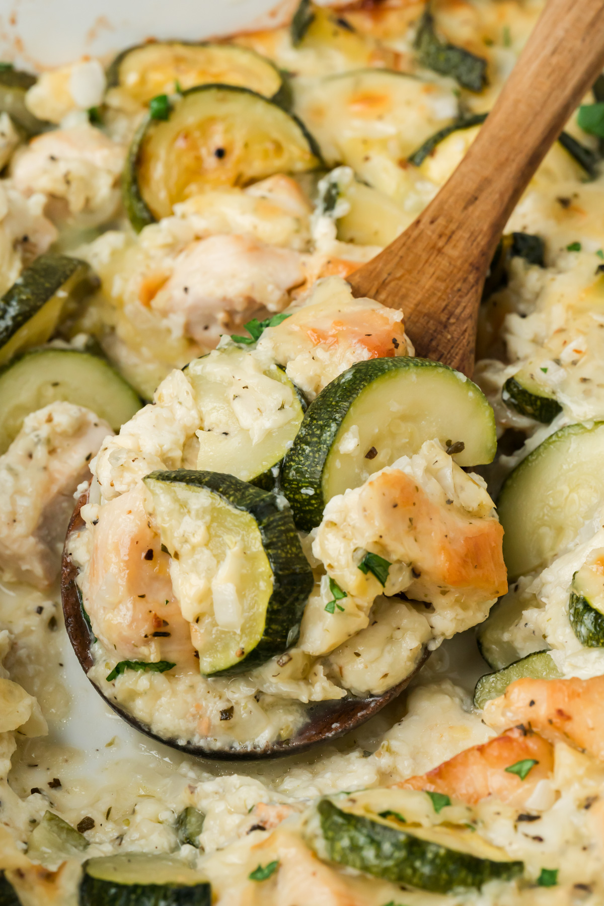 Wooden spoon filled with the chicken zucchini bake.