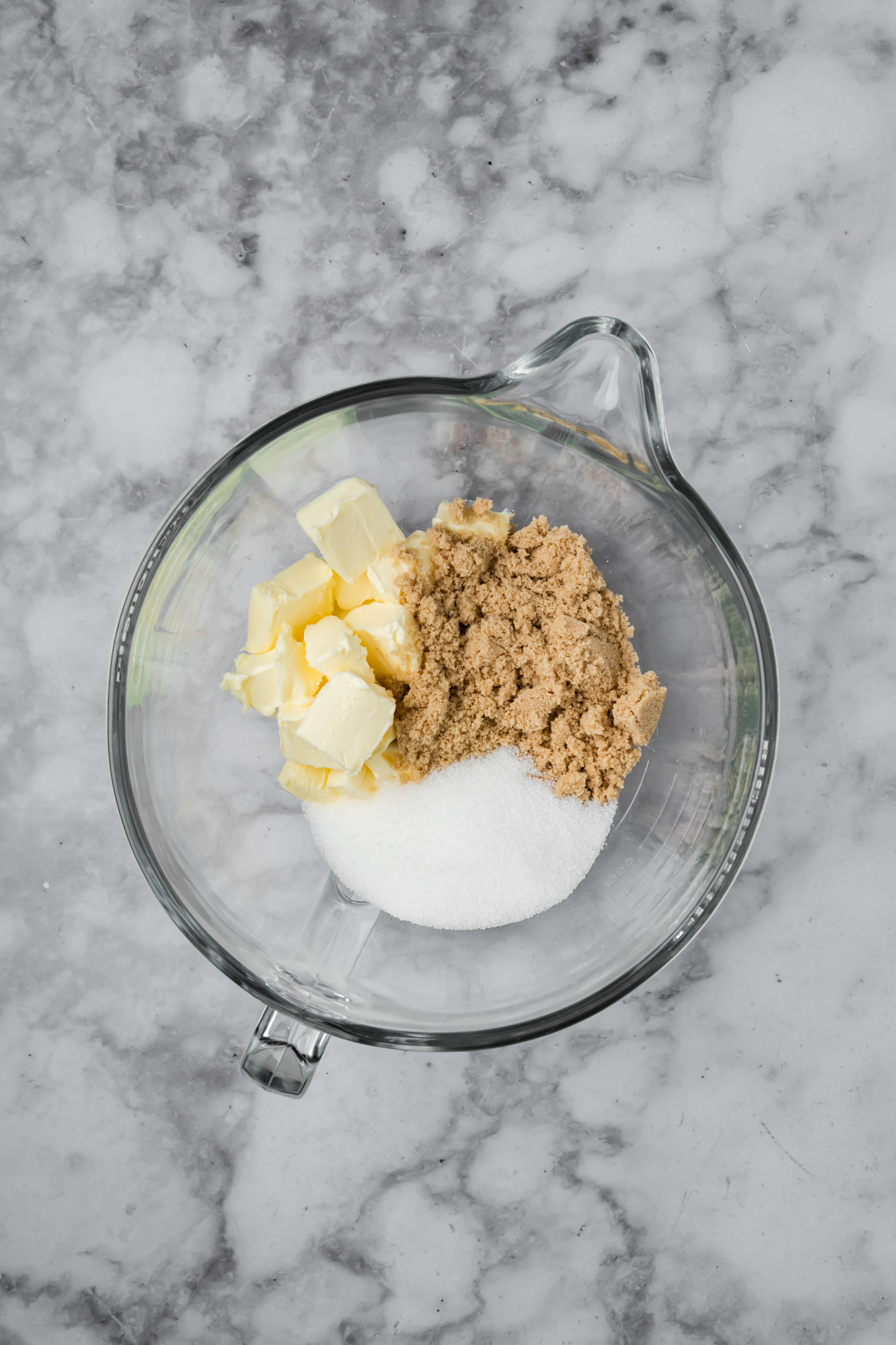 Butter and sugar in a glass mixing bowl. 