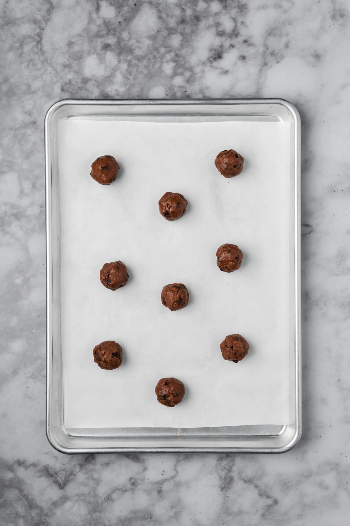 Cookie dough balls on a large baking sheet. 