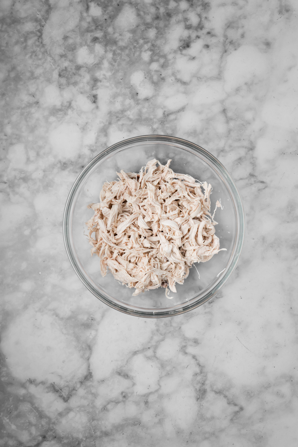 Shredded chicken in a glass bowl.