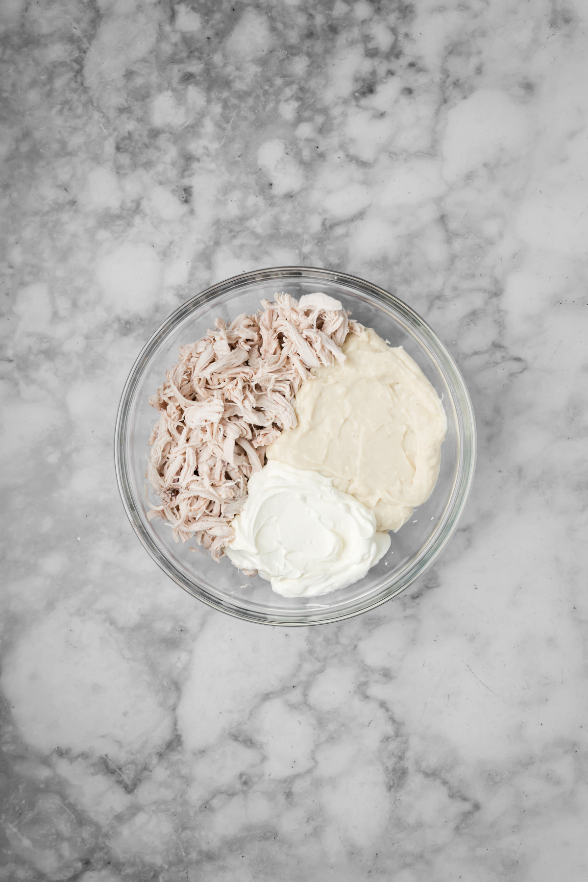 Chicken, cream of chicken soup, and sour cream in a glass bowl.