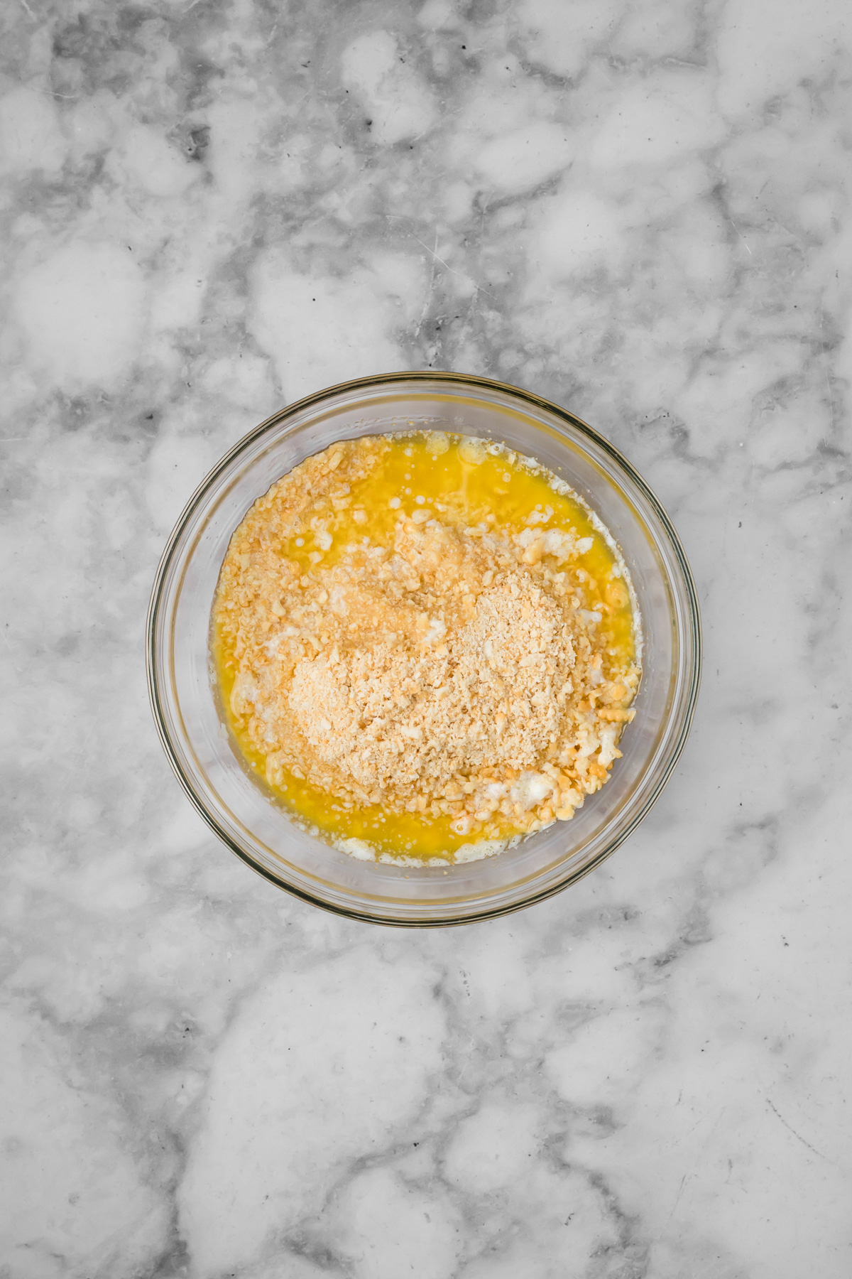 Crumbled crackers and butter in a glass bowl.