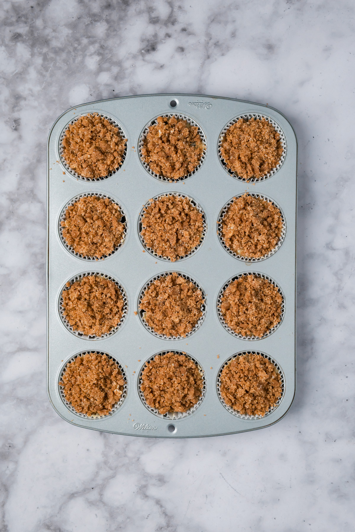 Crumble added on top of the muffin batter in the muffin tin. 