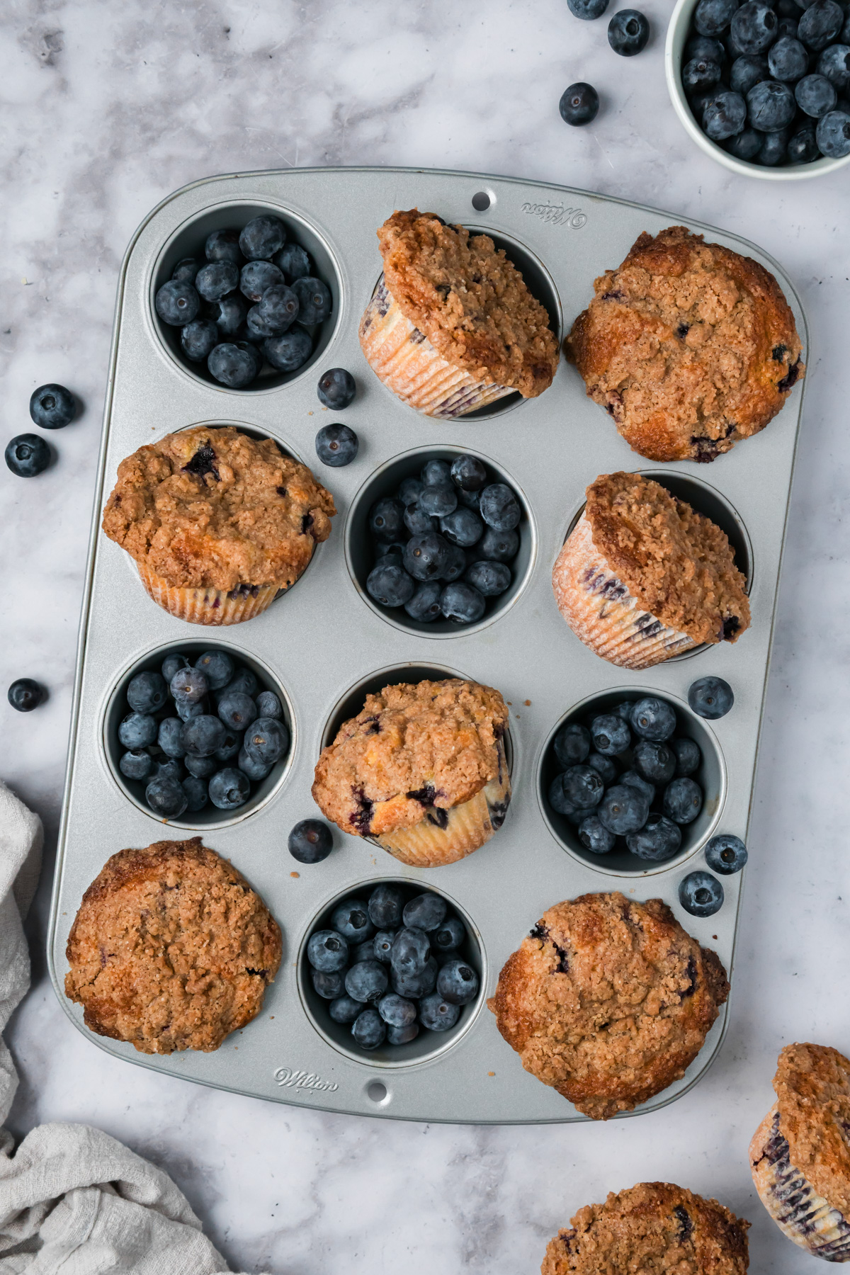 Bakery style blueberry muffins in a muffin tin after baking.