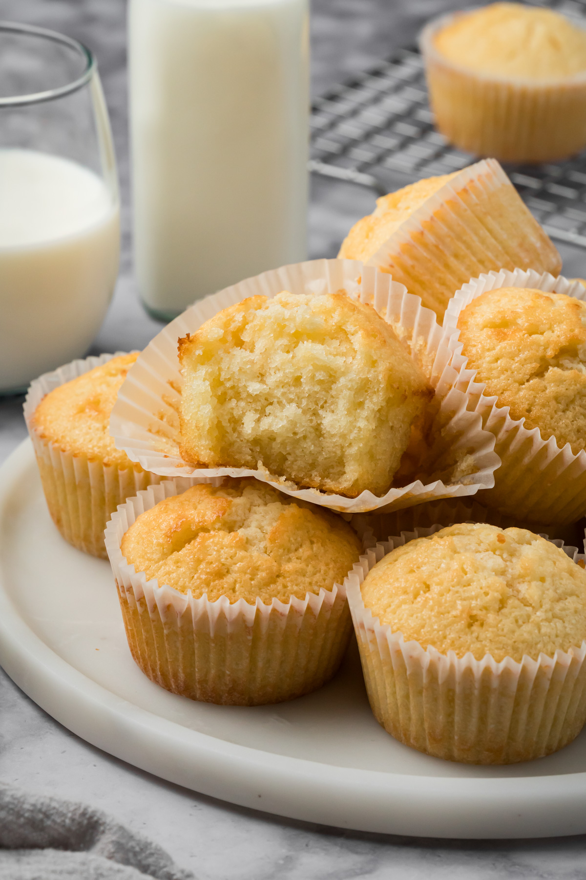 A stack of vanilla muffins with a bite taken out of one. 